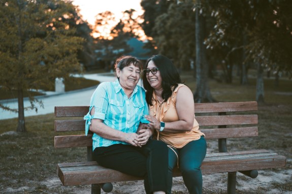 Family laughing while sitting on a park bench